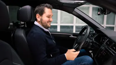 Oliver Winter, Head of service and portfolio management in the security division at Bosch Energy and Building Solutions, in car with smart phone