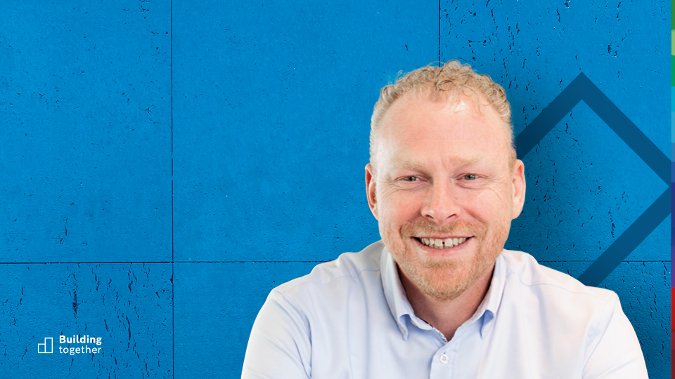 Bosch associate Bernhard Gijzen sitting cross-legged in front of the Bosch logo at the Nieuwegein location.