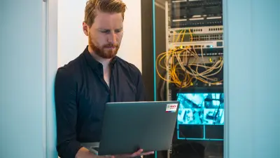 Servicetechniker von Bosch mit Laptop vor Sicherheitstechnik