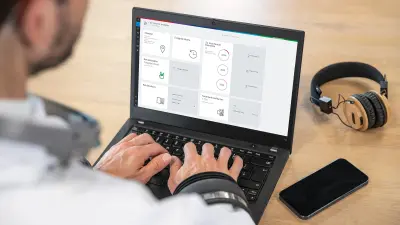 Blick über die Schulter einer Person, die am Laptop arbeitet. Auf dem Bildschirm des Laptops ist das Dashboard des digitalen Service NEXOSPACE Fire System Analyzer zu sehen.