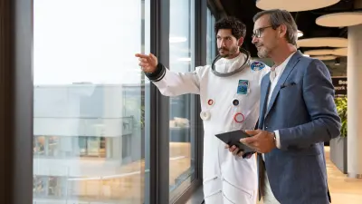 Ein Gebäudemanager mit Tablet ist im Gespräch mit einem Datanauten, der den digitalen Brandschutz für Gebäude symbolisiert.