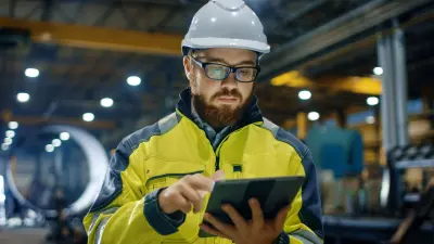 Ingenieur in einer Fabrikhalle tippt auf Tablet