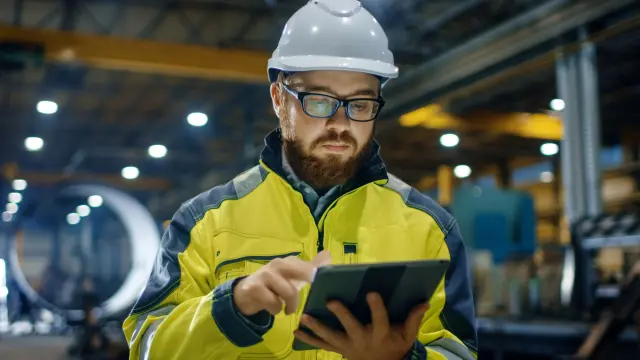 Ingenieur in einer Fabrikhalle tippt auf Tablet