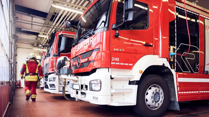 Feuerwehrmann geht neben Einsatzfahrzeugen in Gerätehaus