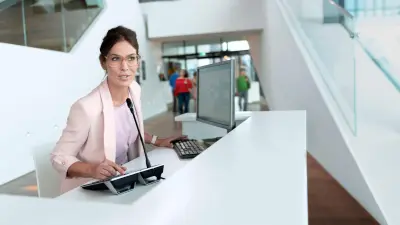 Woman at reception desk with public address and voice alarm system from Bosch Energy and Building Solutions