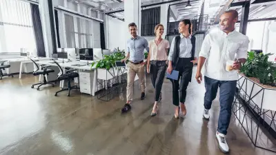 Four young professionals walking together through an office