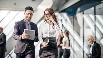 Kollege zeigt anderem Kollegen im Büro etwas auf dem Tablet.