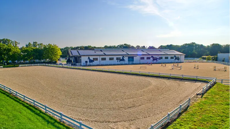 Reitplatz und Stallgebäude in der Sonne