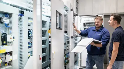Project manager Martin Hartmann and an employee in front of the control cabinet