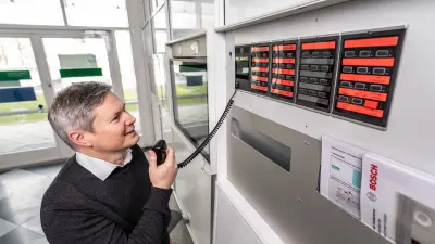 Michael Huck spricht in das Mikrofon neben dem Feuerwehrtableau