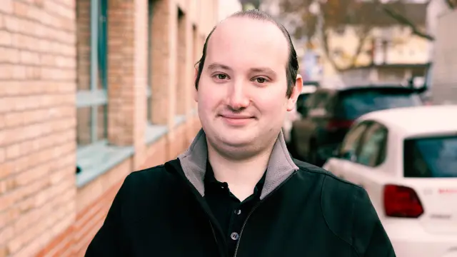Kevin Wilhelm in front of a building with his company car.