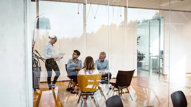 Inspirierende Räume für Kommunikation im Smart Office. Eine Gruppe von Menschen tauscht sich aus.