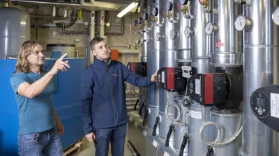 Wood chip plant at Sozialwerk Breisgau, interior, facility manager and Bosch employees in front of the heat distribution system