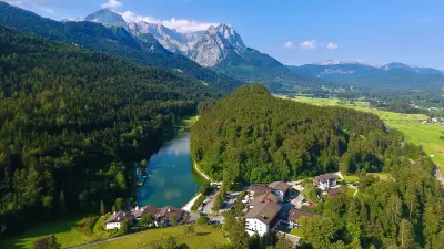 Vogelperspektive auf Hotel und See mit den Alpen im Hintergrund