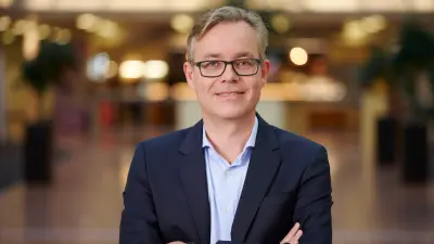 The picture shows a portrait of Mr Henrik Siegle. He is wearing a suit without a tie, glasses, has short hair and a friendly expression.