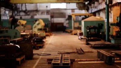 Metin: Paletler ve makinelerle dolu bir ambarın bulanık görüntüsü.