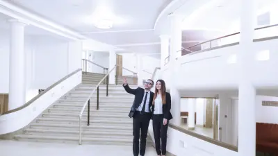 A man and a woman are walking through a museum. The man is pointing and showing her something.