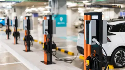 inside of parking garage where a row of electric cars are beeing charged
