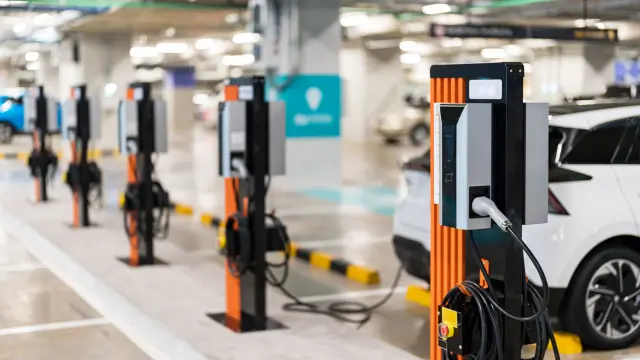 inside of parking garage where a row of electric cars are beeing charged