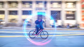 Man on bicycle with hat and backpack in city street. 