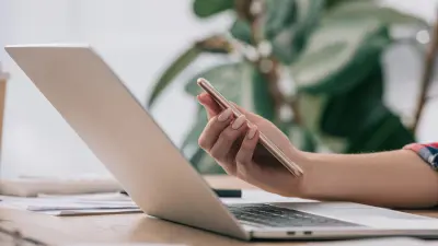 Computer portatile e mano che regge un telefono cellulare