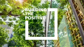 Buildings in a city surrounded by green trees, with sustainable wooden and glass architecture